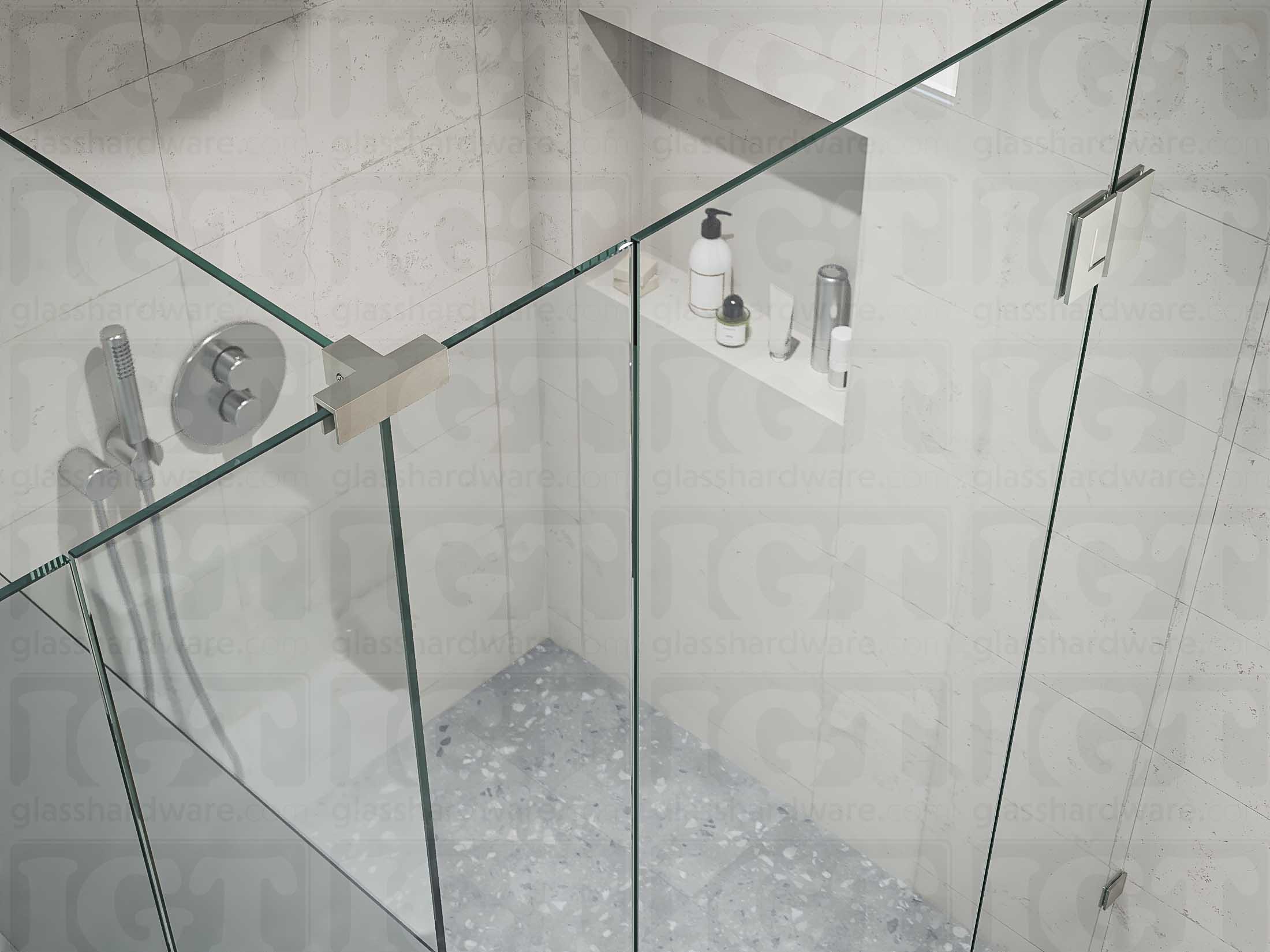 A top view of the T-shaped shower enclosure secured by a Glass-to-Glass T-Junction Sleeve Over Clamp. Its sleek design and Brushed Nickel finish complements the shower's matching hinge and wall mounted clamp.