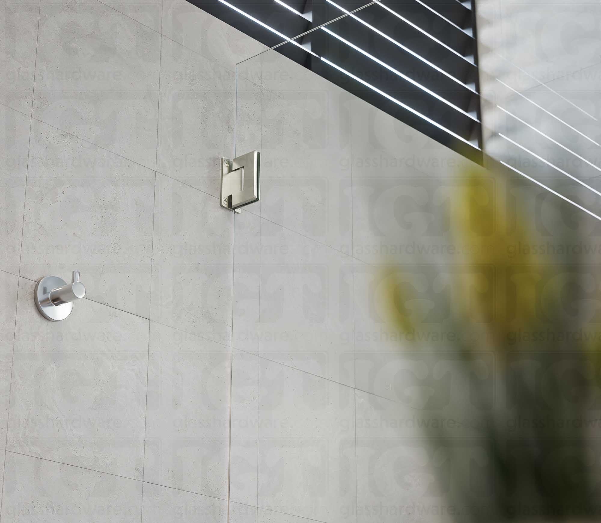 A close-up view from below of the Wall-to-Glass Full Back Bilboa Hinge used in a modern shower door installation. Brushed Nickel.