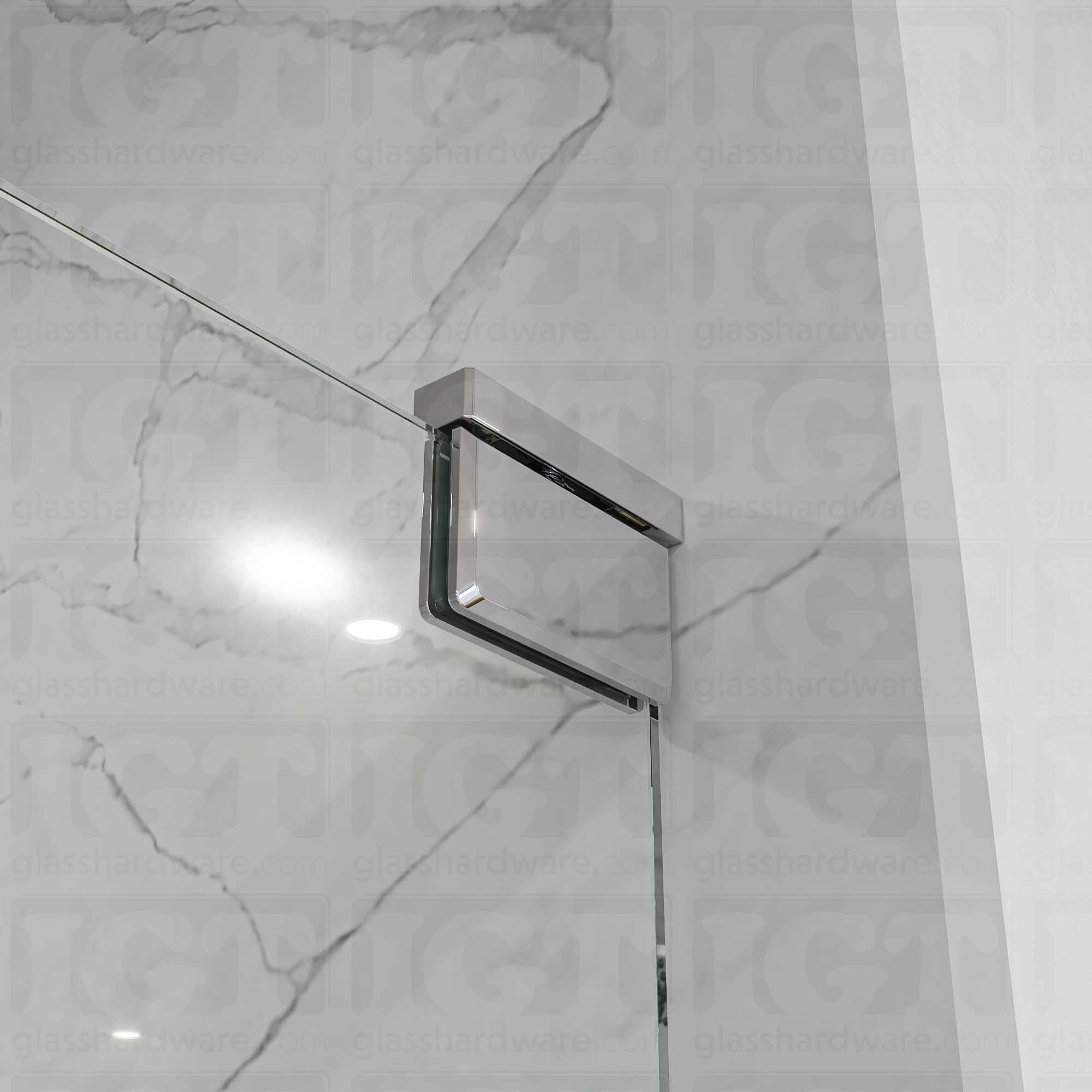 Close-up of the Left Wall Mount Bilboa Pivot Hinge mounted at the top of the glass shower door. The hinge has soft rounded corners and sleek beveled edges, adding a touch elegance to the shower enclosure. Chrome Polished.