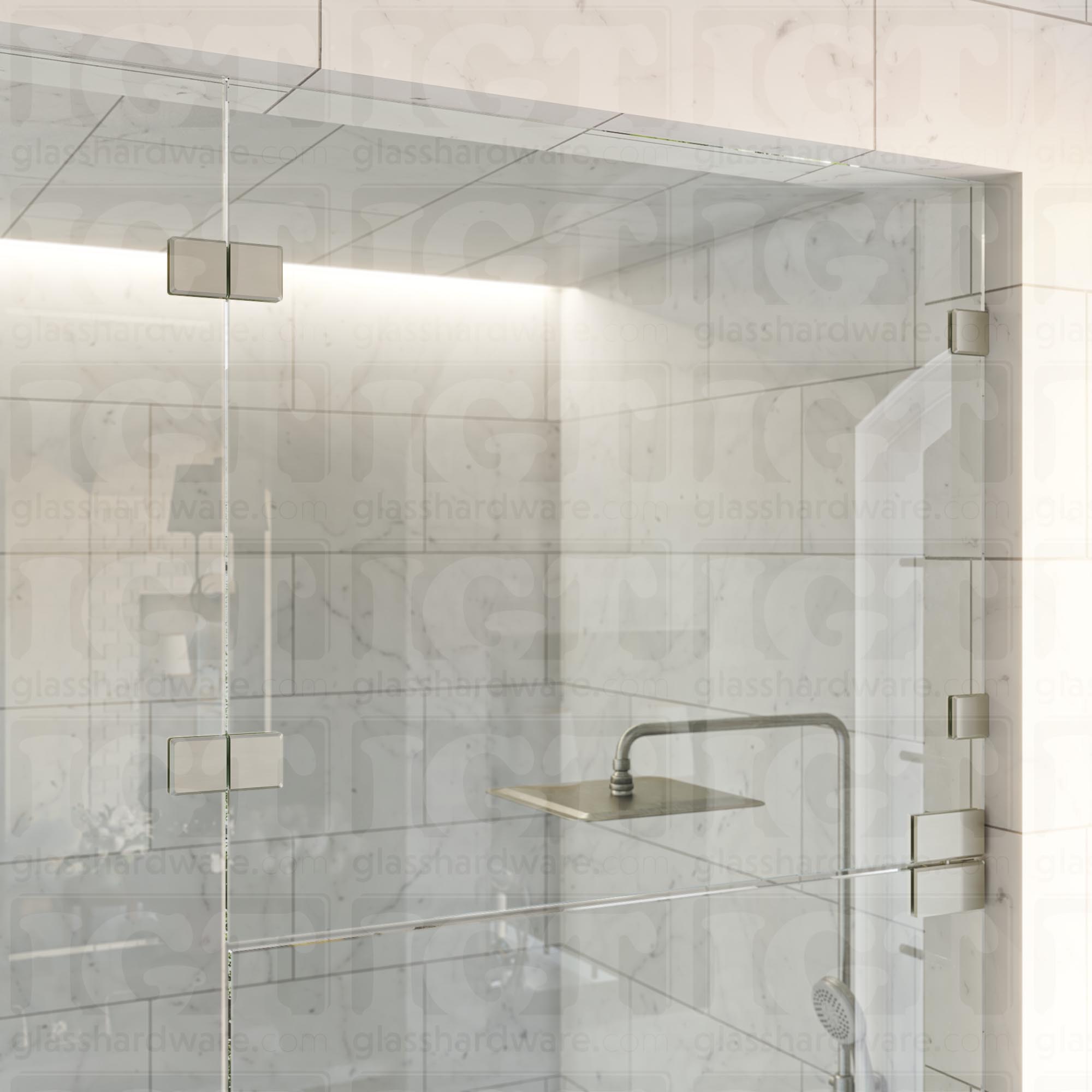 An upper view of the shower's glass panels, secured with Glass-to-Glass 180 Degree Bilboa Clamps (Split Face) alongside a matching hinge for the door. The hardware's corresponding finishes give the shower elegance and cohesiveness. Brushed Nickel.