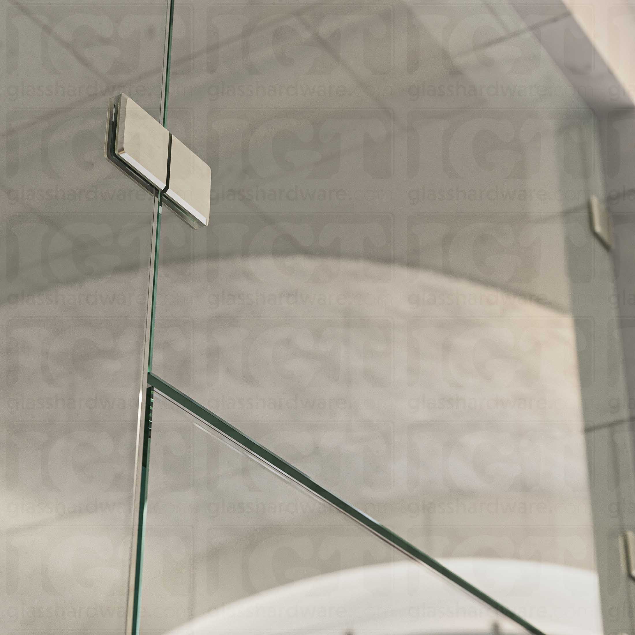 A close-up view of the Glass-to-Glass 180 Degree Bilboa Clamp (Split Face), installed on a frameless glass shower enclosure. The clamp's Solid Brass construction provides a secure and durable connection for the shower's panels. Brushed Nickel.