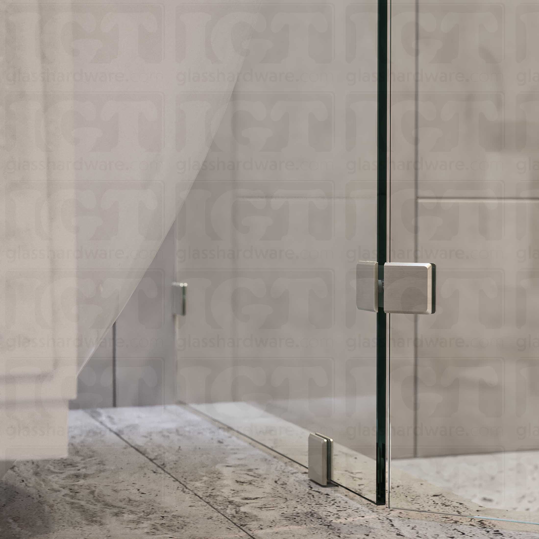 A bottom view of the neo-angle shower's fixed panels, secured by a floor mounted clamp, a wall mounted clamp, and the Glass-to-Glass 135 Degree Bilboa clamp. The shower's look is enhanced by the hardware's matching finish and beveled-edge design. Brushed Nickel.