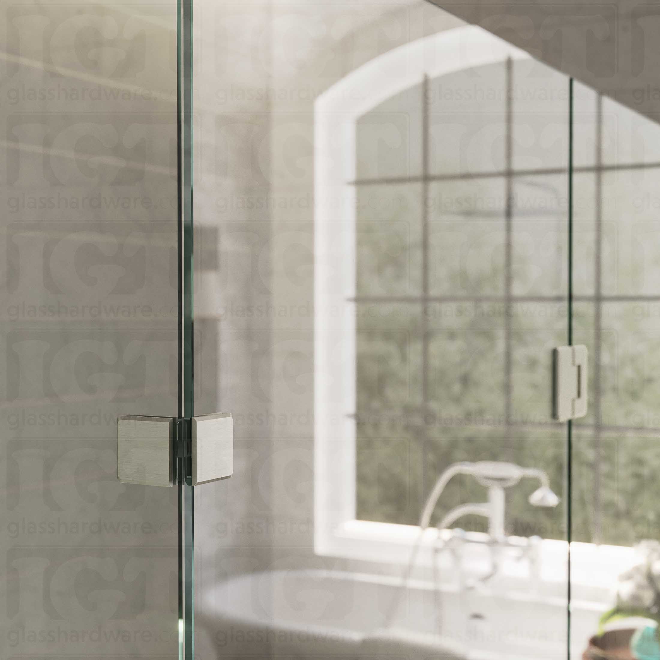 An upper view of the shower's glass panels, secured with a Glass-to-Glass 90 Degree Bilboa Clamp alongside a matching hinge. The hardware's corresponding finishes and beveled-edge design give the shower elegance and cohesiveness. Brushed Nickel.