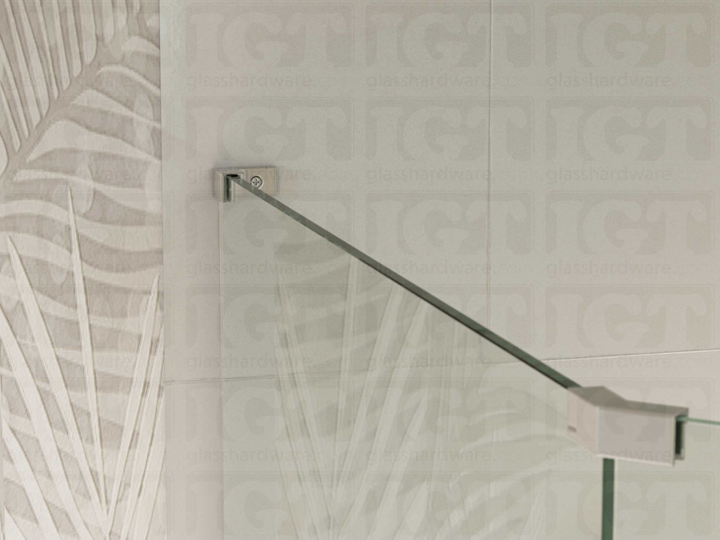 A view of the glass shower enclosure's upper section. The fixed panel is secured to the wall with a Left Wall-to-Glass Sleeve Over Clamp, and joined to an adjacent panel with a glass-to-glass clamp. Chrome Polished.