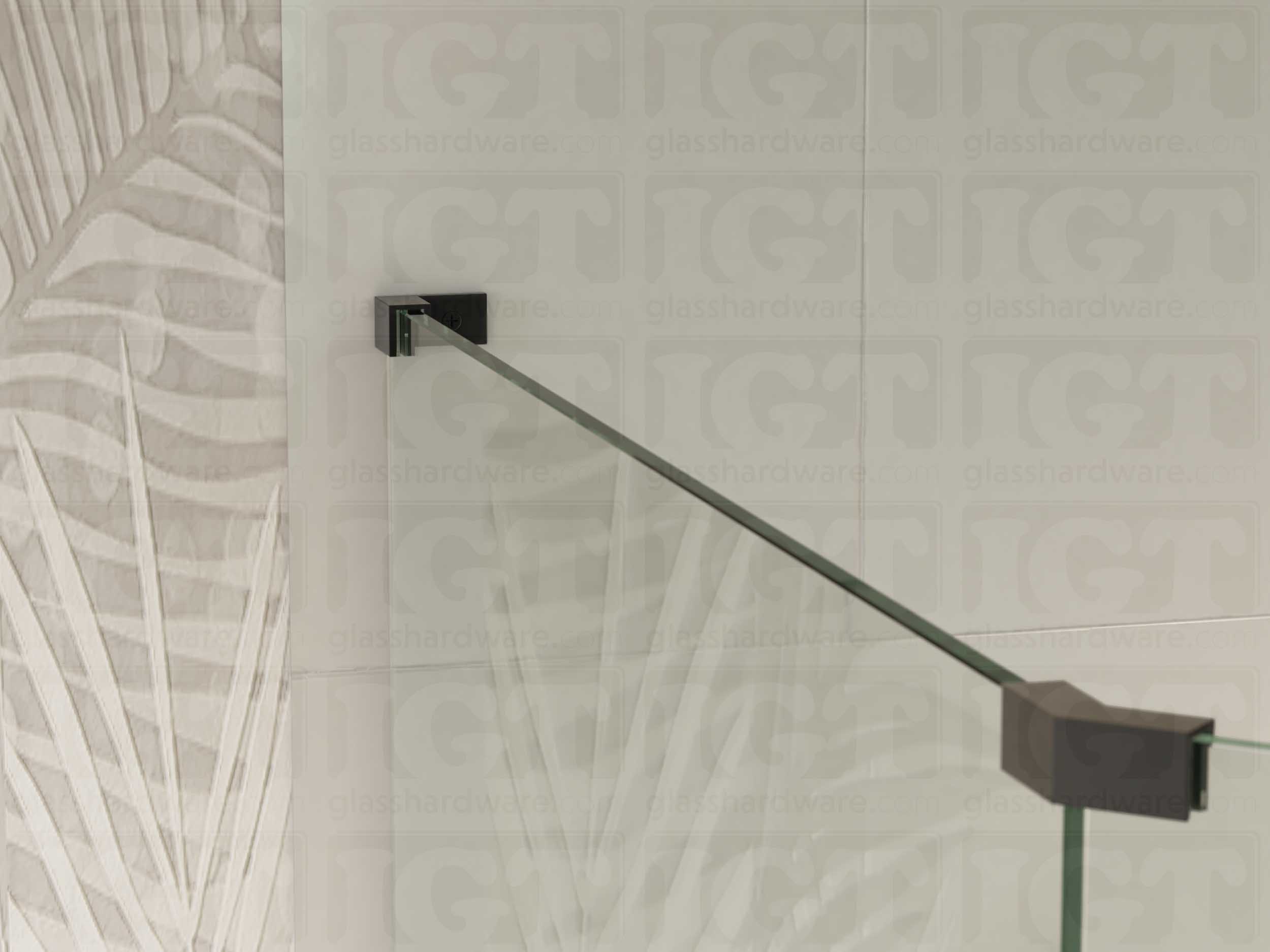 A view of the glass shower enclosure's upper section. The fixed panel is secured to the wall with a Left Wall-to-Glass Sleeve Over Clamp, and joined to an adjacent panel with a glass-to-glass clamp. Matte Black.