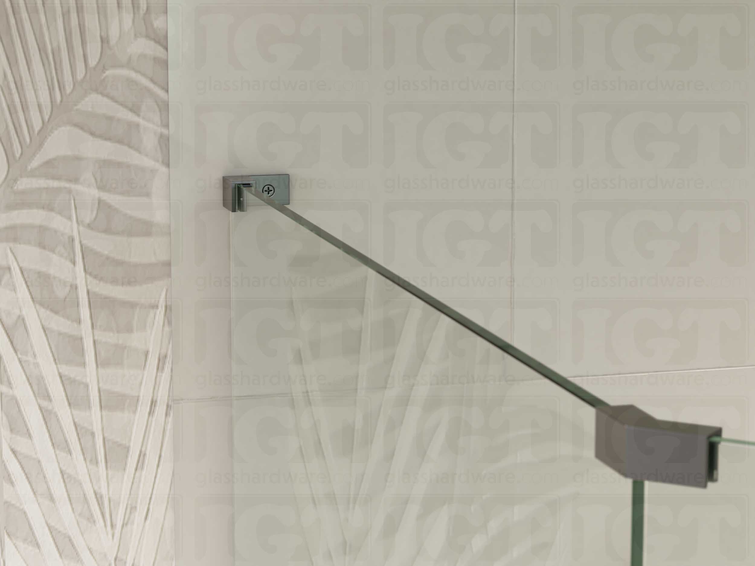 A view of the glass shower enclosure's upper section. The fixed panel is secured to the wall with a Left Wall-to-Glass Sleeve Over Clamp, and joined to an adjacent panel with a glass-to-glass clamp. Polished Gun Metal.