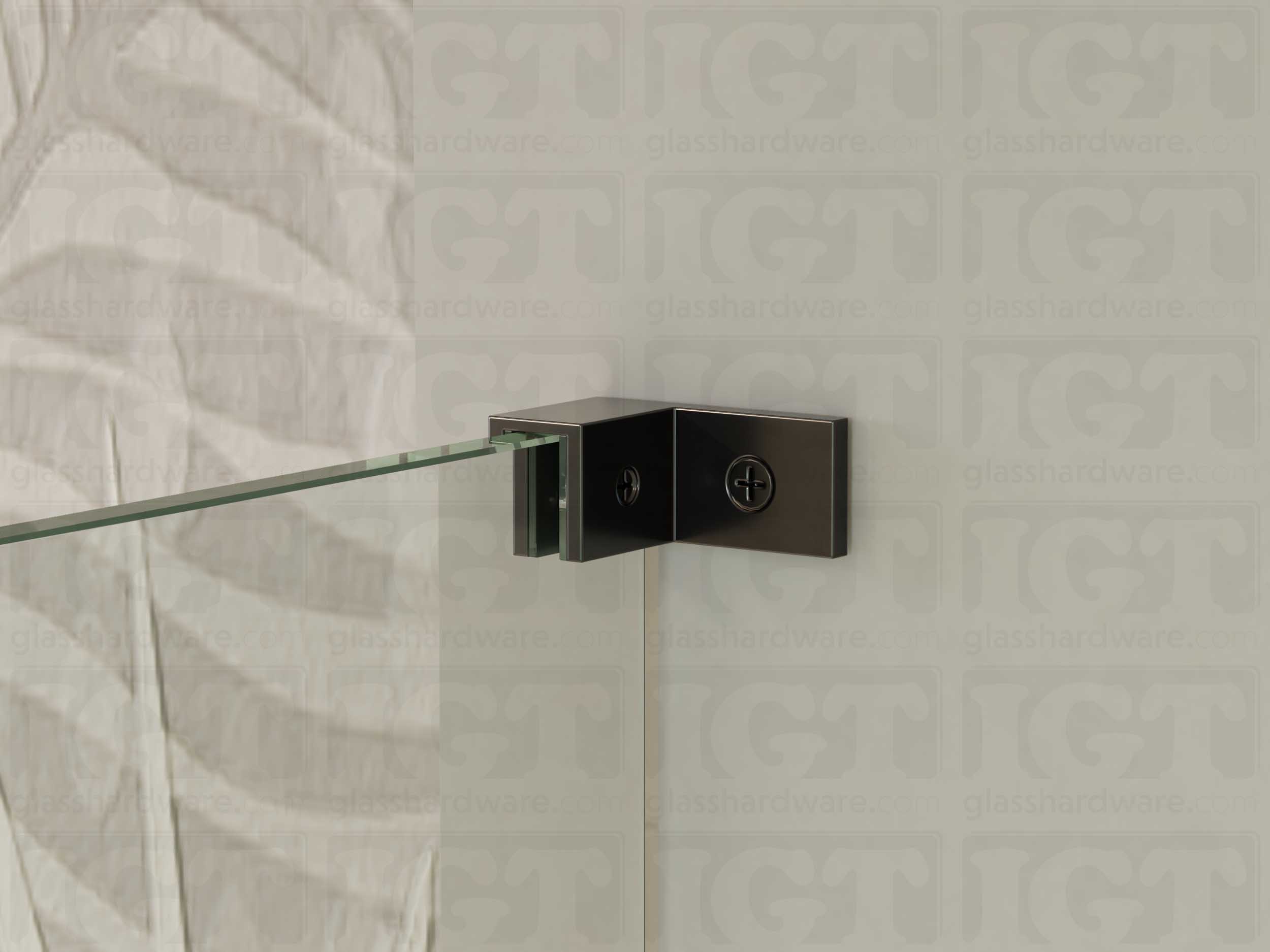 A close up of the Left Wall-to-Glass Sleeve Over Clamp installed on a frameless glass shower enclosure. The clamp is securely mounted to the shower's wall, providing additional support to the overall installation. Polished Gun Metal.