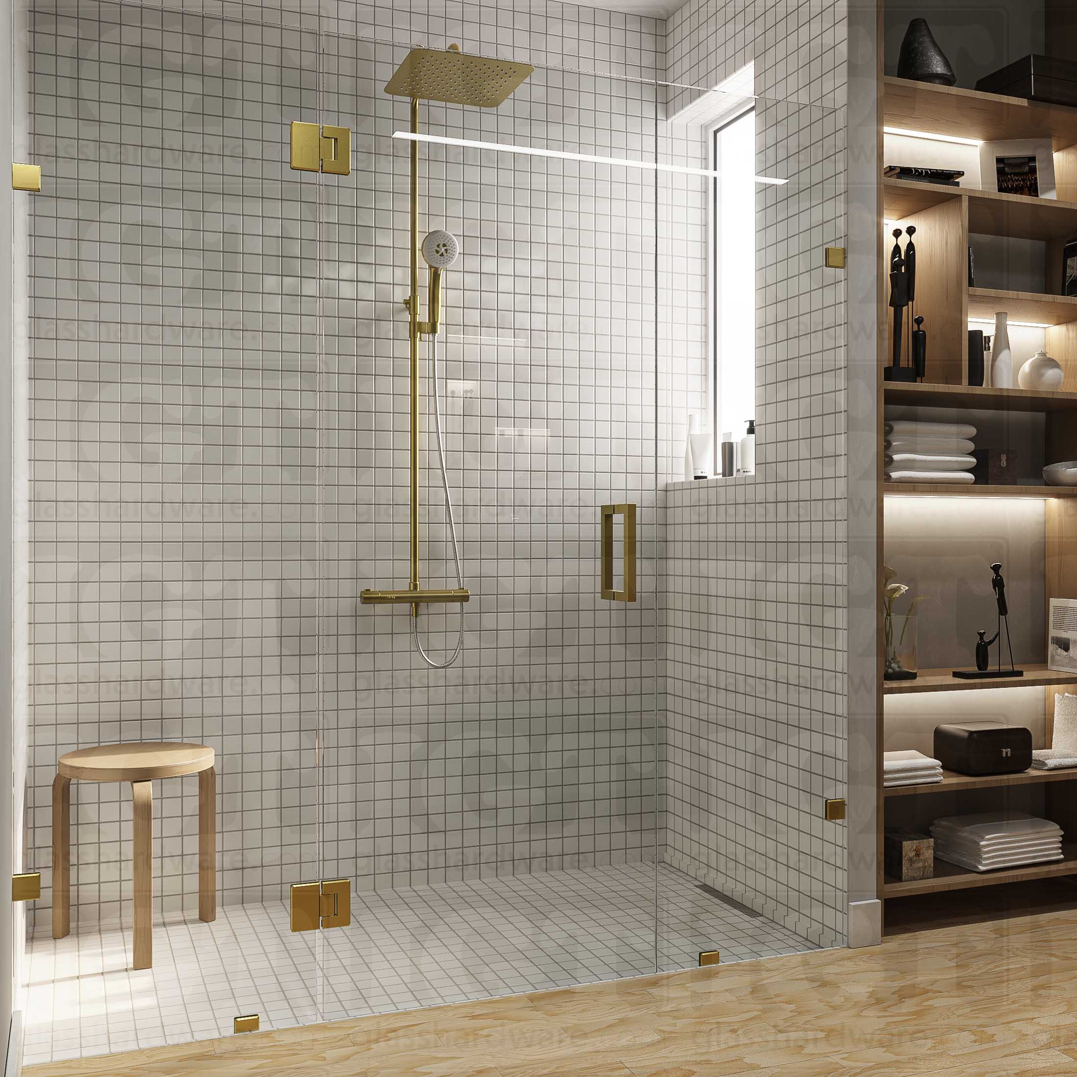 A modern bathroom with a frameless glass shower enclosure, fixed to the wall using Wall-to-Glass Bilboa Clamps. The shower's white tile walls complement the rest of the bathroom's light wood flooring and furnishings. Gold Brushed.