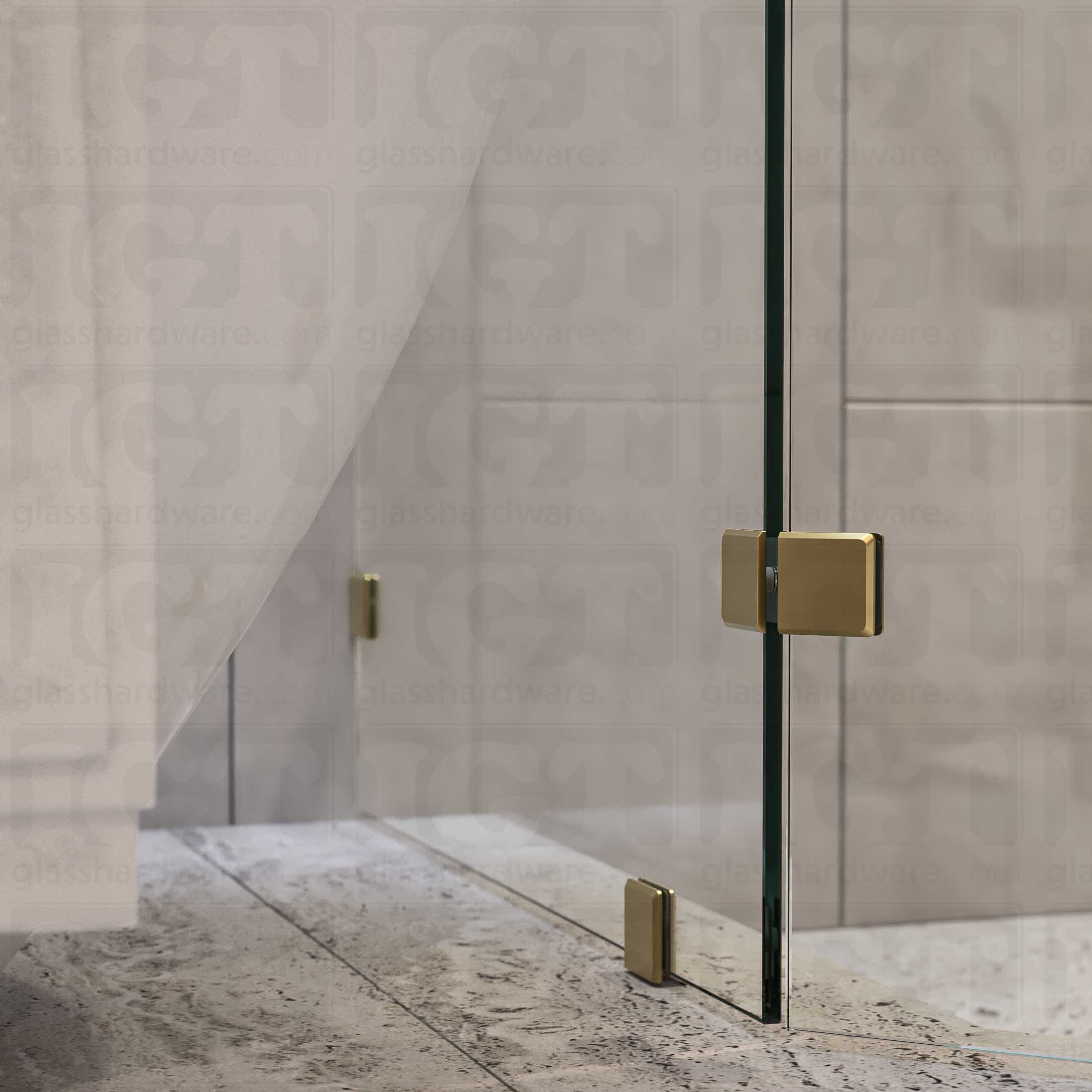 A bottom view of the neo-angle shower's fixed panels, secured by a floor mounted clamp, a wall mounted clamp, and the Glass-to-Glass 135 Degree Bilboa clamp. The shower's look is enhanced by the hardware's matching finish and beveled-edge design. Gold Brushed