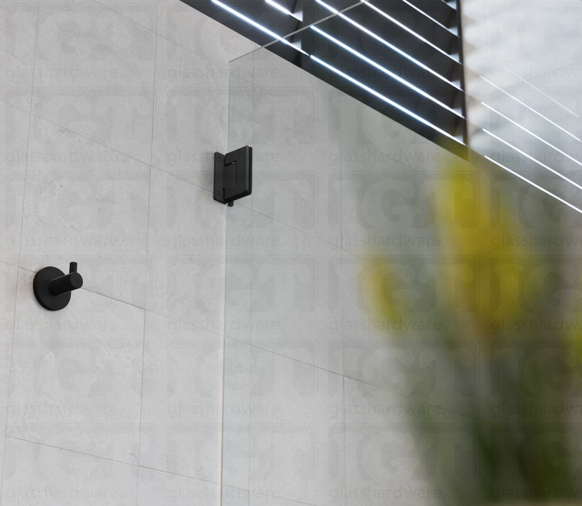 A close-up view from below of the Wall-to-Glass Full Back Bilboa Hinge used in a modern shower door installation. Matte Black.