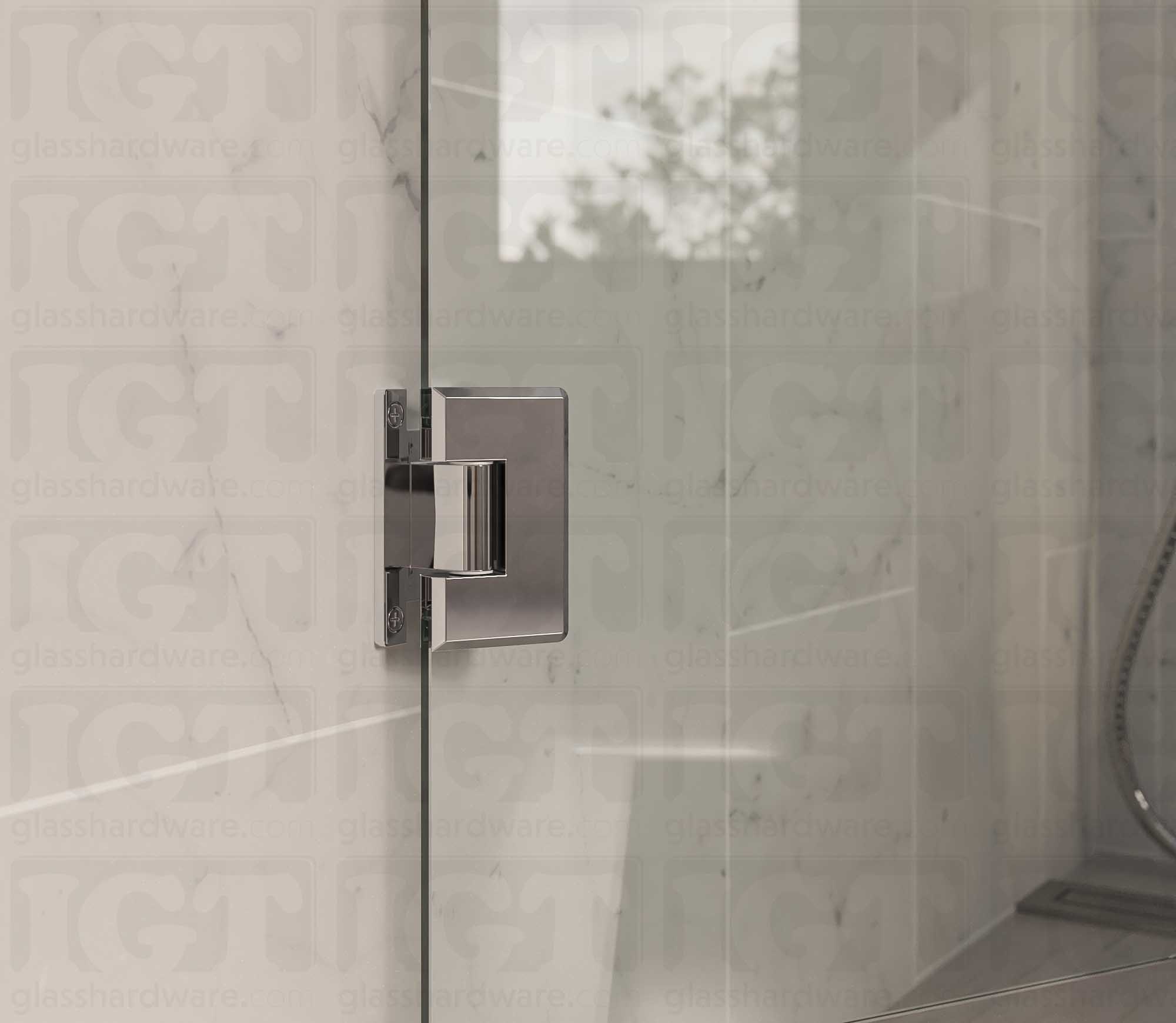 A close up view of the Heavy Duty Wall-to-Glass “H” Back Bilboa Hinge installed on a frameless glass shower door. The bathroom's natural lighting reflects along the hinge's sleek beveled edges, adding dimension to the overall design. Chrome Polished.