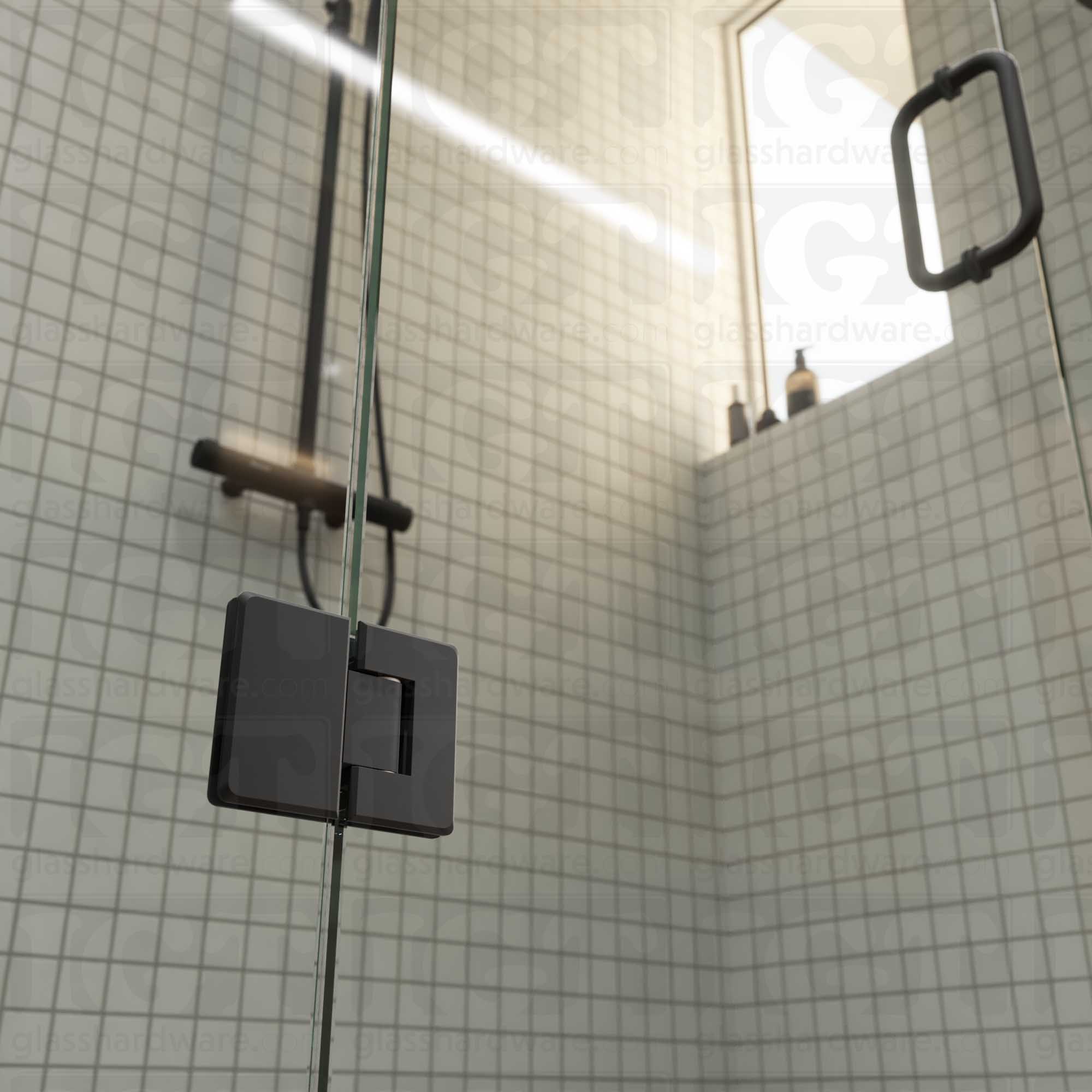 A close-up view of the bottom Glass-to-Glass 180 Degree Bilboa Hinge installed on a modern shower door in the closed position, showcasing its beveled-edge design in more detail. Matte Black.