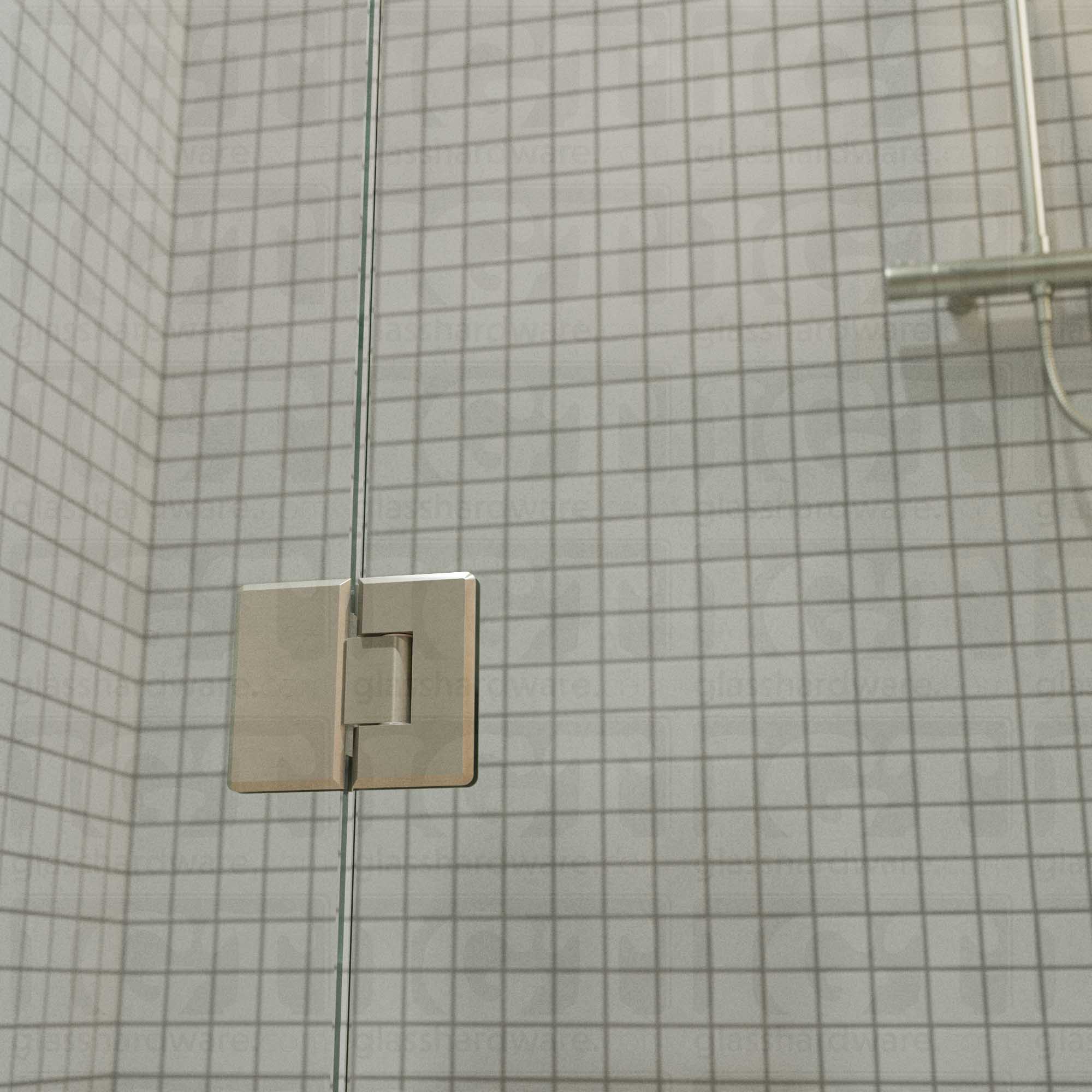 A close-up view of the bottom Heavy Duty Glass-to-Glass 180 Degree Bilboa Hinge installed on a modern shower door. Brushed Nickel.