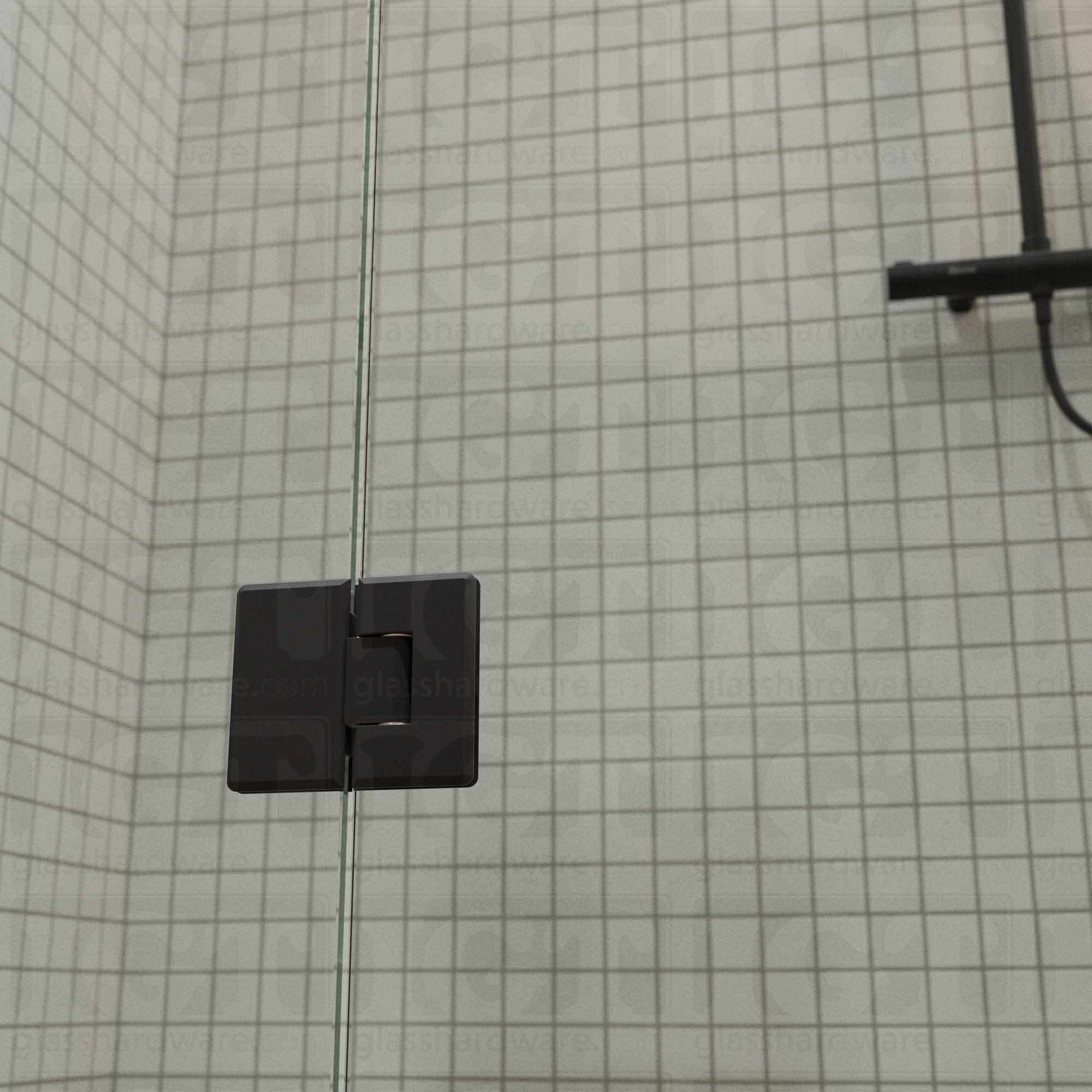 A close-up view of the bottom Heavy Duty Glass-to-Glass 180 Degree Bilboa Hinge installed on a modern shower door. Matte Black.