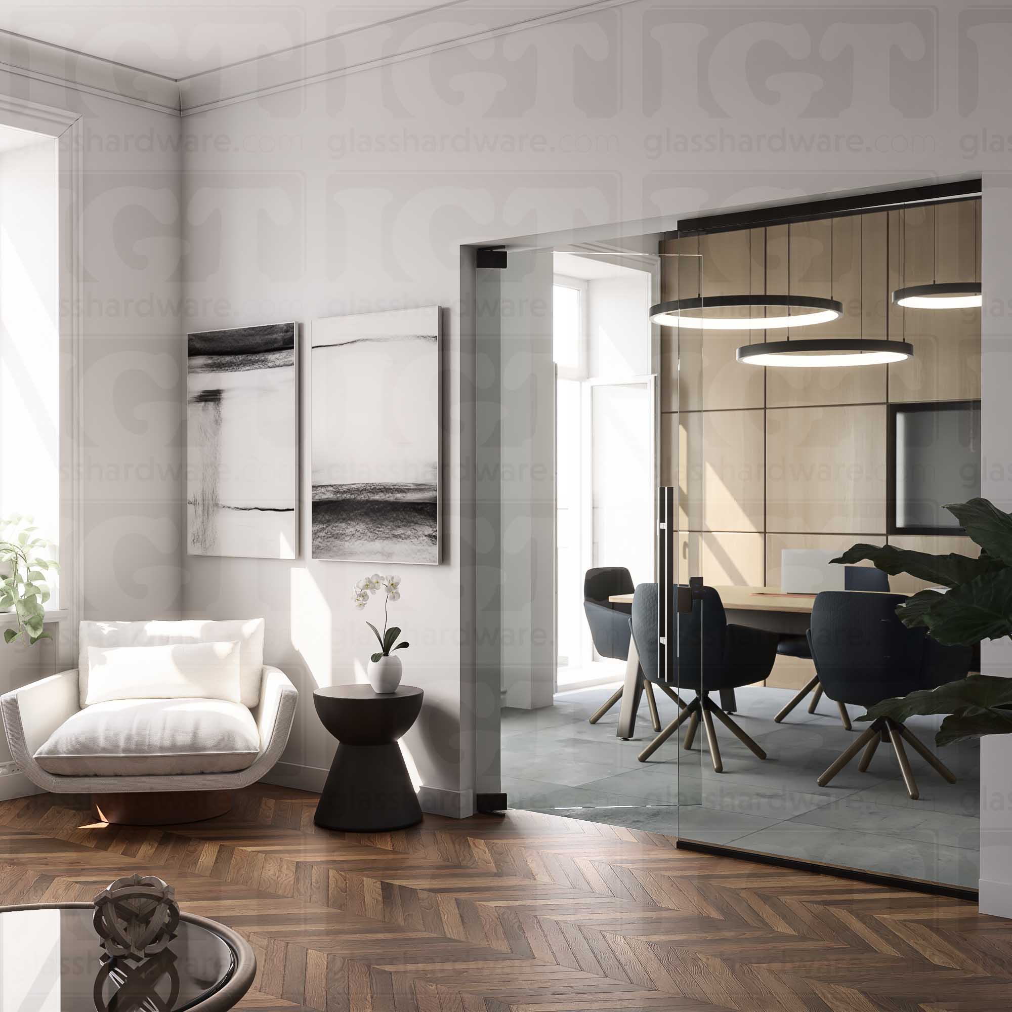 A modern interior view with a glass door seperating a cozy lounge area from a sleek conference room. The glass door is mounted with two Heavy Duty Top and Bottom Bilboa Pivot Hinges. Soft, natural lightning reflects off of the hinge's brass construction, while contrasting with the lounge's warm wood herringbone floor. Matte Black.