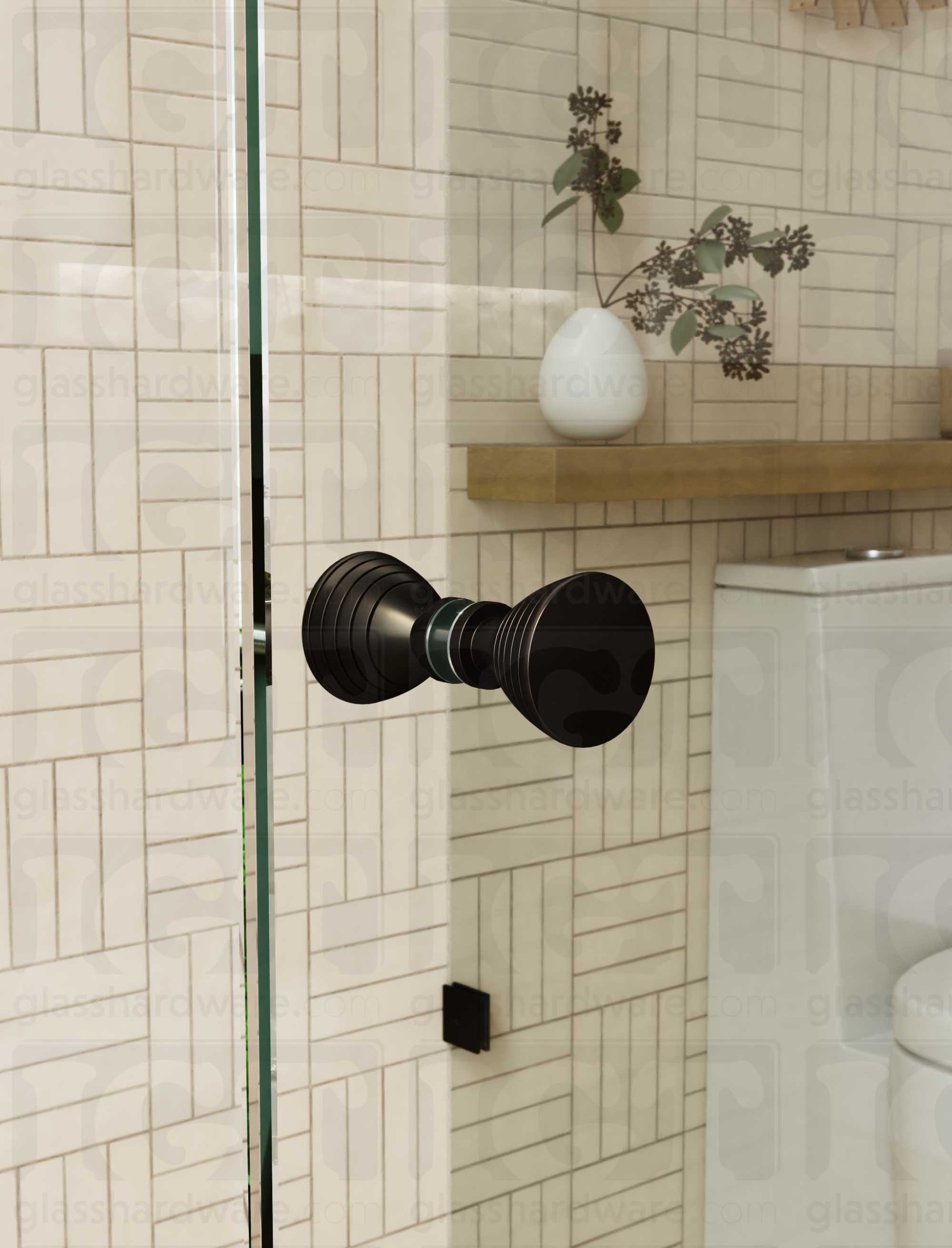 A close up of the Ribbed Bow Tie Style Back-to-Back Door Knob installed on a glass shower door. The door knob's back-to-back design is tightly secured to the glass door. Oil Rubbed Bronze.