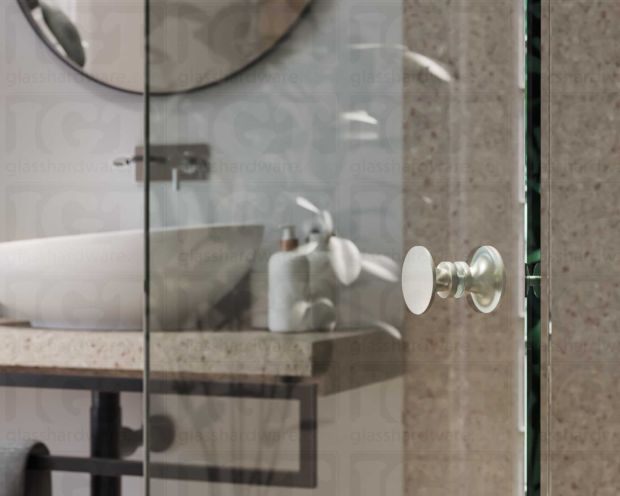 A close up of the Traditional Style Back-to-Back Door Knob installed on a glass shower door. The door knob's back-to-back design is tightly secured to the glass door. Brushed Nickel.