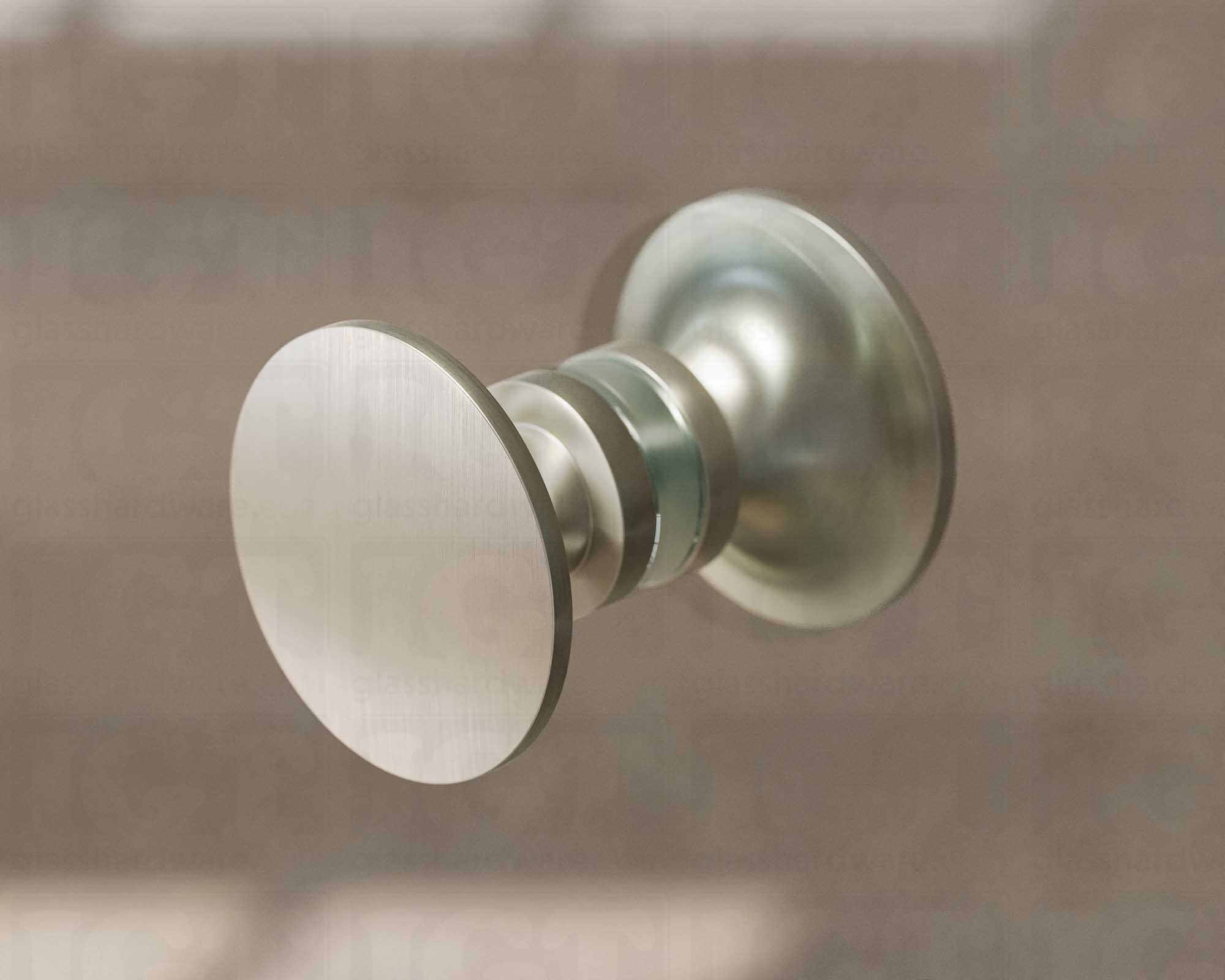 A close up of the Traditional Style Back-to-Back Door Knob installed on a glass shower door. Soft natural light highlights the knob's Brushed Nickel finish.