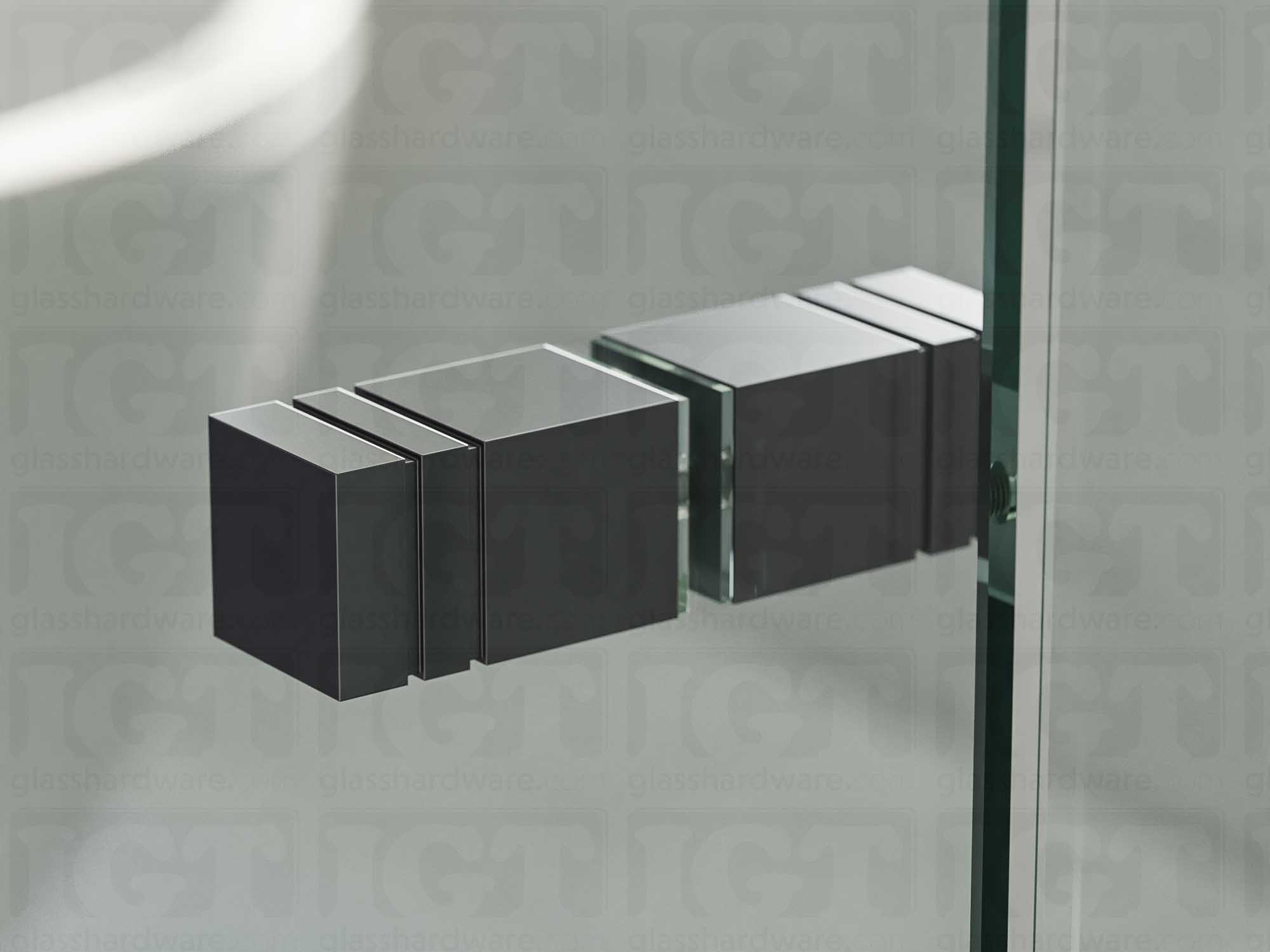 A close up of the Square Back-to-Back Door Knob installed on a glass shower door. Soft natural light highlights the knob's Polished Gun Metal finish.